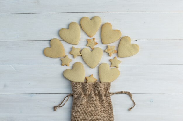 Quelques biscuits éparpillés à partir d'un sac sur fond de bois, pose à plat.