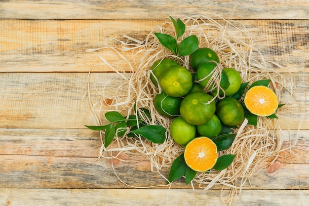 Photo gratuite quelques mandarines avec des feuilles sur planche de bois