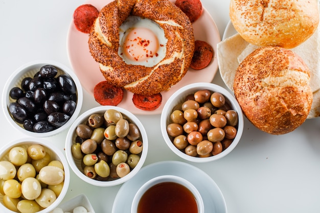 Quelques œufs Avec Saucisse Avec Une Tasse De Thé, Bagel Turc, Olive, Pain Dans Une Assiette Sur Une Surface Blanche, Vue Du Dessus