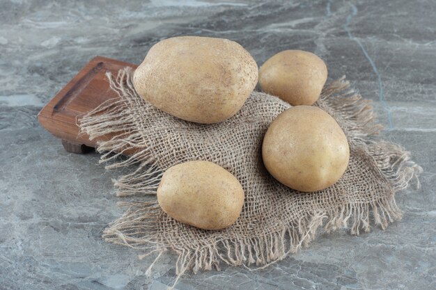 Quelques pommes de terre sur le dessous de plat, à bord sur la table de marbre.