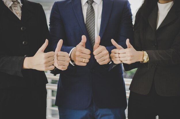 Équipe des activités debout devant le bureau entreprise prospère avec affichage des pouces vers le haut