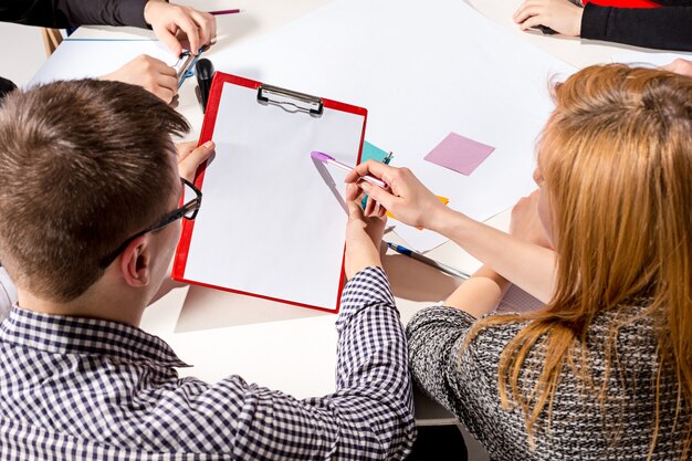 Équipe assise derrière le bureau, vérifiant les rapports, parlant. Le concept d'entreprise de collaboration, travail d'équipe, réunion