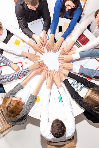 Équipe assise derrière le bureau, vérifiant les rapports, parlant et se reliant les mains. Vue de dessus. concept d'entreprise de collaboration, travail d'équipe, réunion