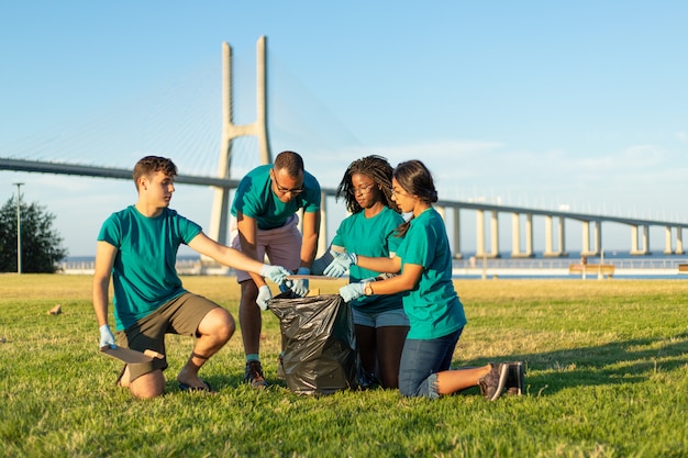 Équipe de bénévoles multiethnique retirant les déchets de l'herbe