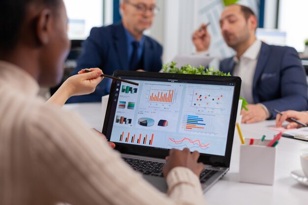 Équipe commerciale multiethnique assise à table dans un centre de bureaux parlant du projet lors d'une réunion dans une salle d'audience