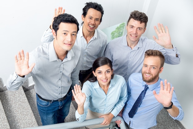 Équipe commerciale souriante agitant sur l&#39;escalier de bureau