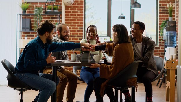 Équipe diversifiée de collègues ayant un partenariat réussi et se sentant heureux du travail d'équipe professionnel. Des gens joyeux célébrant ensemble un accord de collaboration lors d'une réunion dans la salle de réunion.