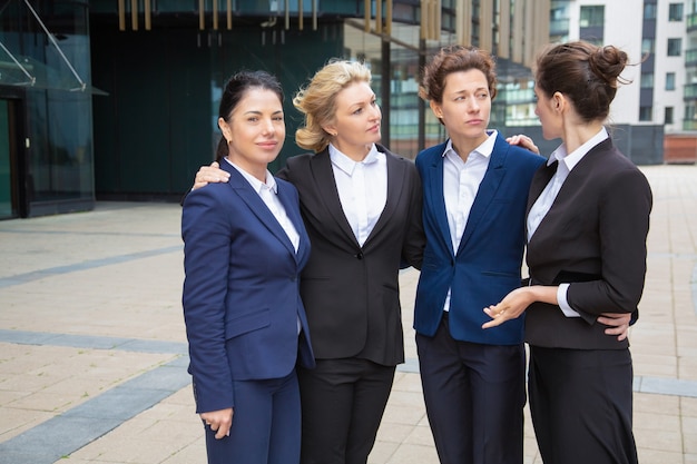 Équipe de femmes d'affaires debout ensemble à l'extérieur, se soutenant mutuellement, discutant du projet. Vue de face. Concept de communauté et de travail d'équipe