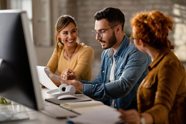 Équipe de jeunes gens d'affaires qui passent par la paperasse tout en travaillant ensemble au bureau L'accent est mis sur l'homme d'affaires