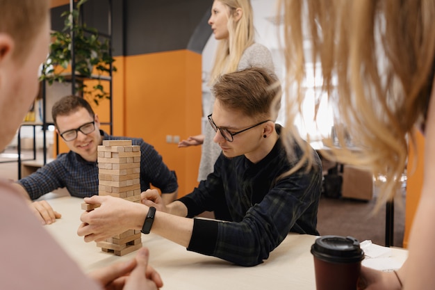 Équipe mixte jouant au jeu de blocs de bois au bureau