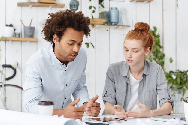 Équipe multiethnique de réflexion créative de jeunes architectes ambitieux remue-méninges au bureau blanc