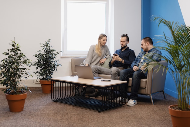 Équipe de trois personnes travaillant sur ordinateur portable au bureau sur le canapé