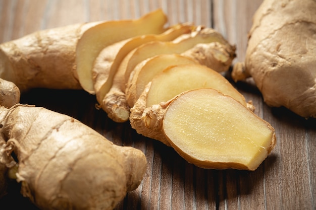 Racine de gingembre frais et tranché sur une table en bois.