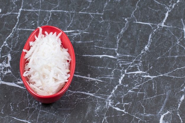 Photo gratuite radis frotter sur une petite râpe pour la préparation de la salade dans un bol orange.