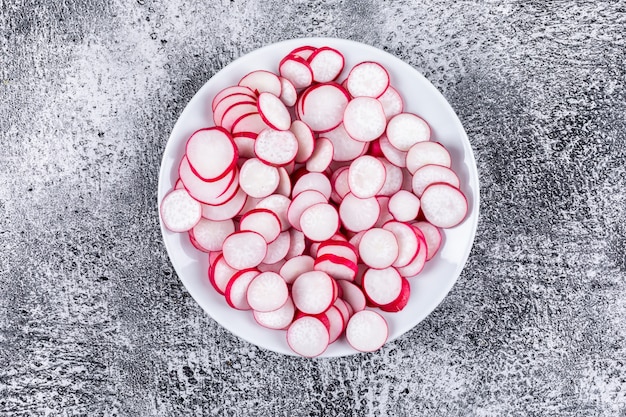 Radis rouges frais hachés dans une assiette blanche