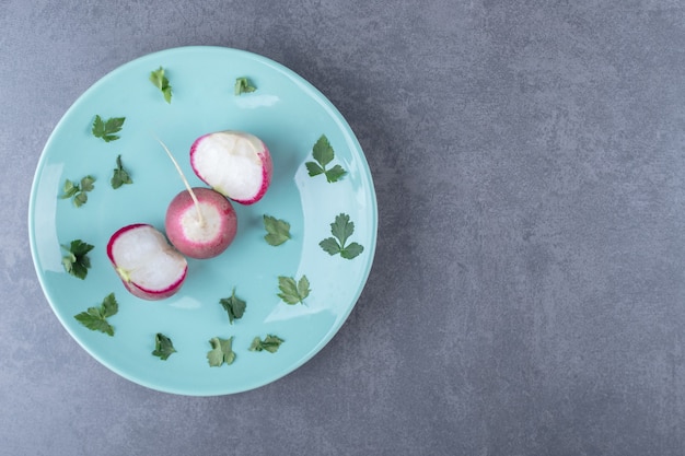 Radis et verdure sur l'assiette, sur la surface en marbre.