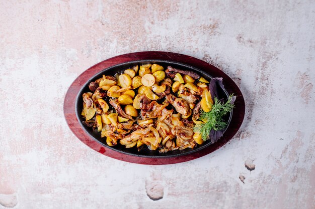 Ragoût de champignons avec des haricots et des châtaignes avec un bouquet d'aneth dans une casserole noire.