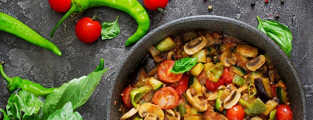 Ragoût chaud d'aubergine épicée, poivron, tomate, courgette et champignons. Mise à plat. Vue de dessus.