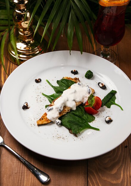 Ragoût de poisson dans une sauce crémeuse, tomate, persil sur l&#39;assiette, couteau, fourchette