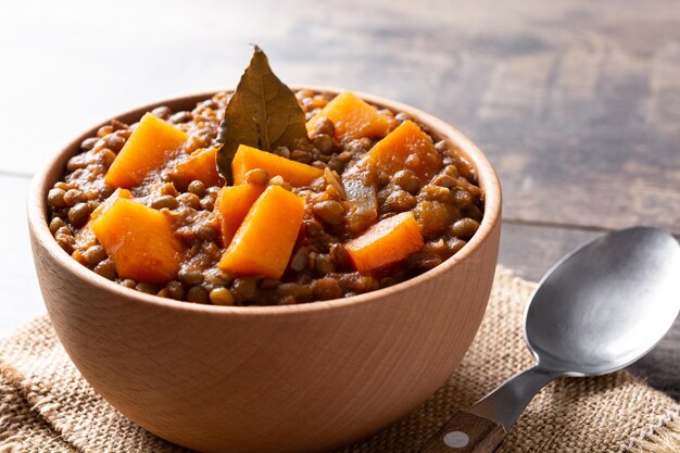 Ragoût de ragoût de lentilles à la citrouille et à la carotte dans un bol sur une table en bois