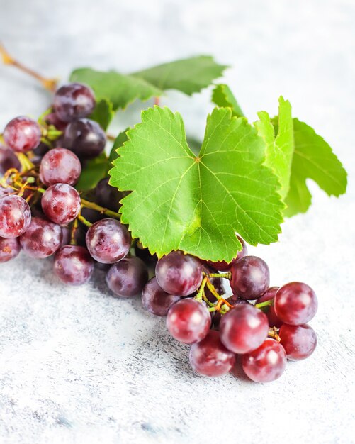 Raisin rouge mûr avec des feuilles sur blanc.