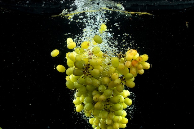 Photo gratuite raisin vert éclabousser dans l'eau en noir