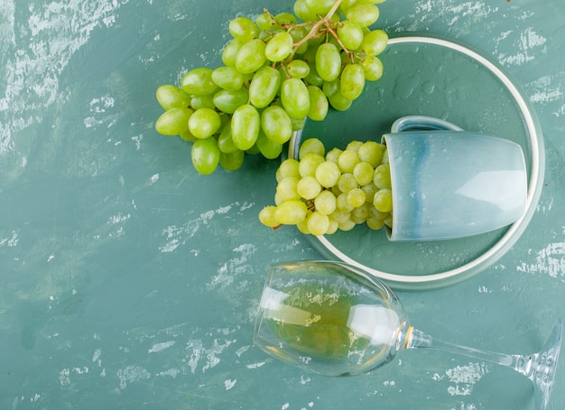 Raisins dans une tasse avec boisson à plat sur fond de plâtre et plateau