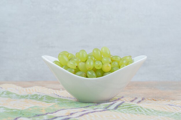 Raisins frais dans un bol blanc sur nappe.