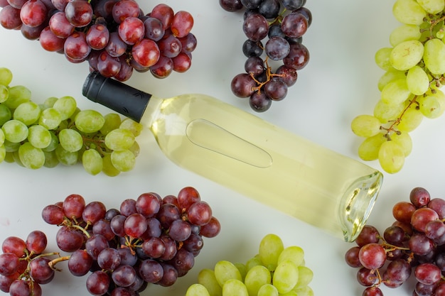Raisins mûrs avec une bouteille de vin sur blanc,