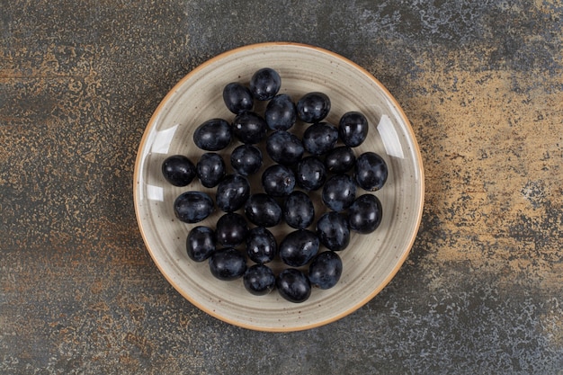 Raisins noirs frais sur plaque en céramique.