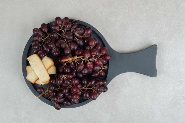 Raisins rouges frais et tranches de fromage sur tableau noir