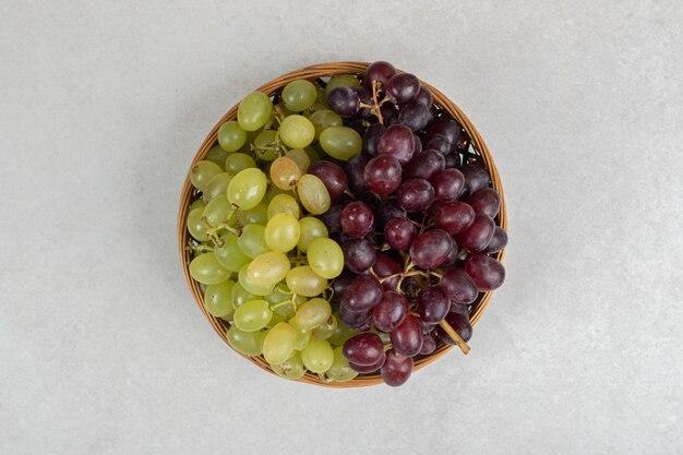 Raisins rouges et verts frais dans un panier en bois