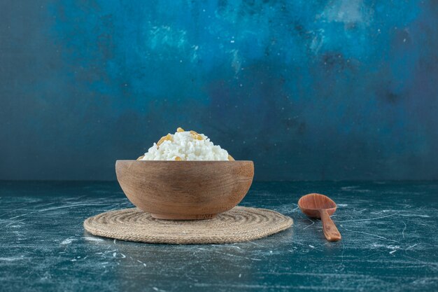 Raisins secs sur un bol de riz au lait à côté d'une cuillère , sur fond bleu. photo de haute qualité