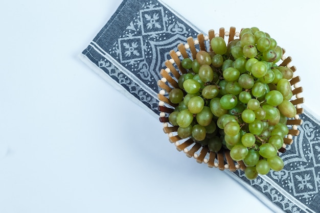 Raisins verts dans un panier plat poser sur fond blanc et torchon de cuisine