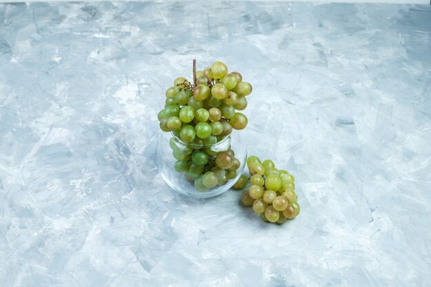 Raisins verts dans un pot en verre sur un fond gris grungy. vue grand angle.