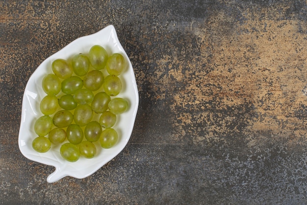 Raisins verts frais sur plaque en forme de feuille.