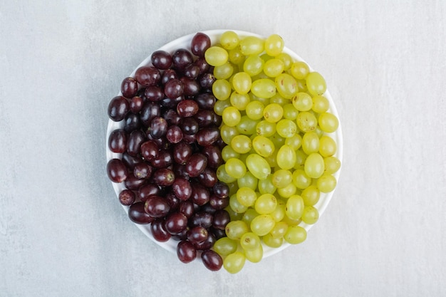 Raisins violets et verts sur plaque blanche. photo de haute qualité
