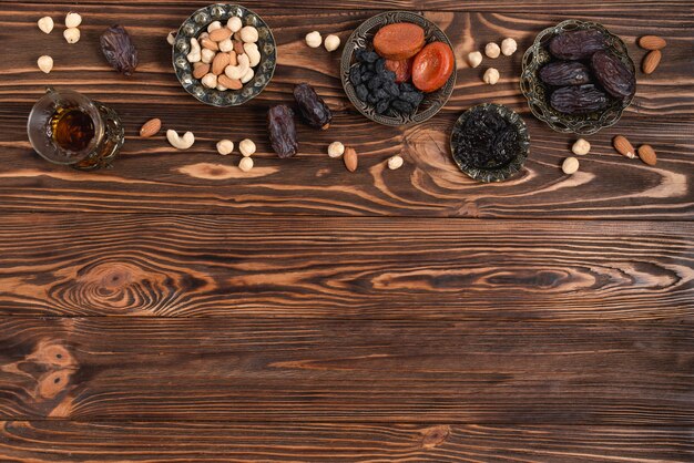 Ramadan dattes fraîches; fruits secs; Noix et verre à thé à base de plantes sur un bureau en bois