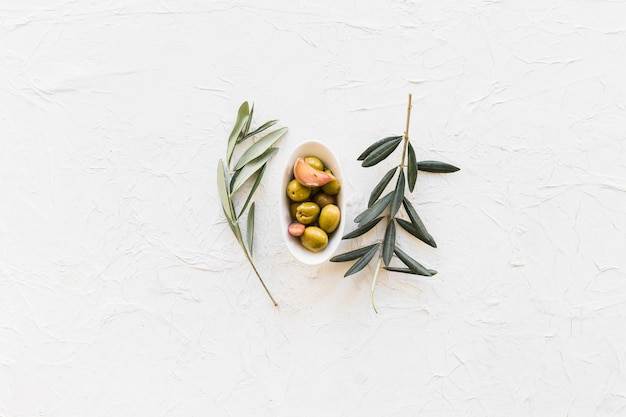 Rameaux avec bol d&#39;olives et gousse d&#39;ail sur fond texturé