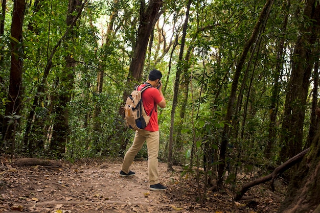 Randonneur avec sac à dos en prenant une photo dans la forêt