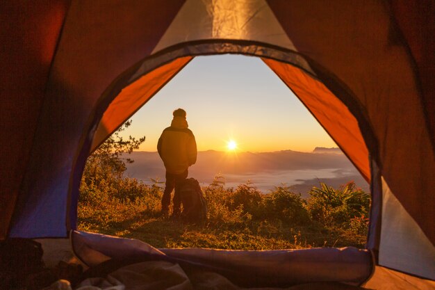 Randonneur se tenir au camping près de la tente orange et sac à dos dans les montagnes