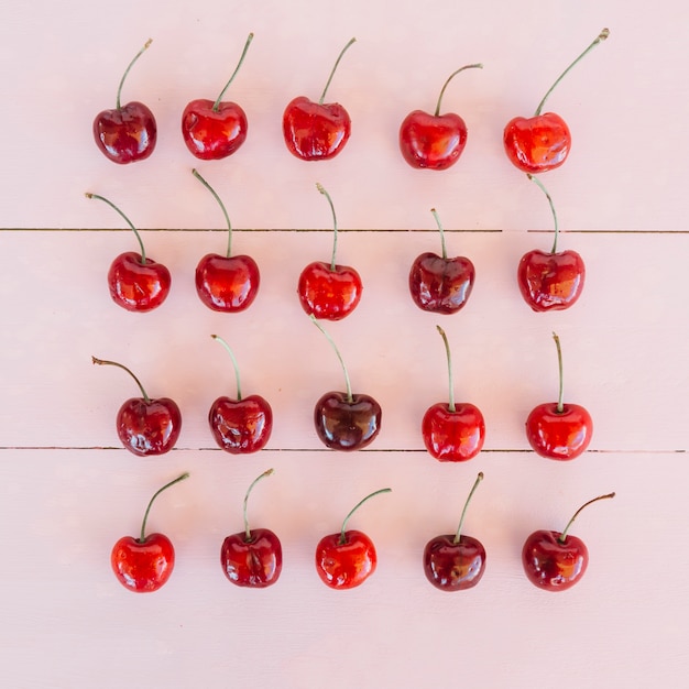 Rangée de cerises juteuses mûres sur fond en bois rose