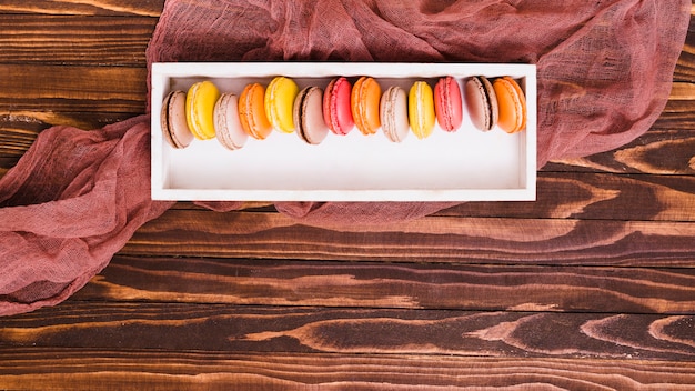 Rangée de macaron dans la boîte en bois blanche au-dessus de la table