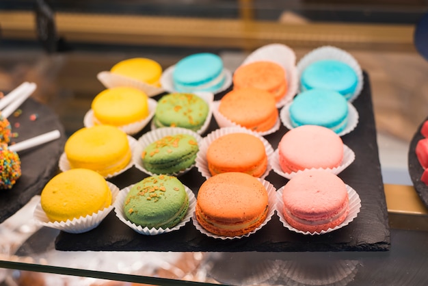 Rangée de macarons colorés sur la plaque d&#39;ardoise dans la vitrine