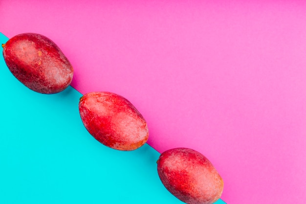 Rangée de mangues rouges sur double fond rose et bleu