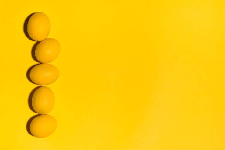 Photo gratuit rangée d'oeufs de pâques jaunes sur une table jaune