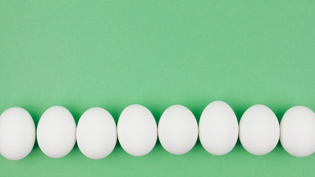 Rangée d&#39;oeufs de poule blanche sur la table verte