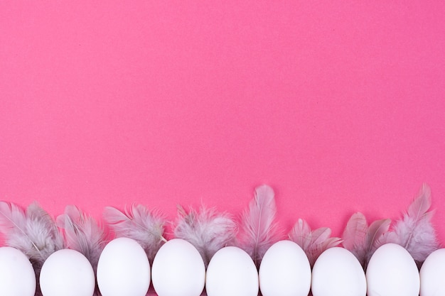 Photo gratuite rangée d'oeufs de poule blancs avec des plumes