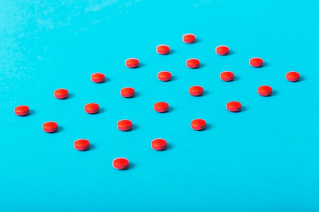 Rangée de pilules rouges disposées en forme rectangulaire sur le fond bleu