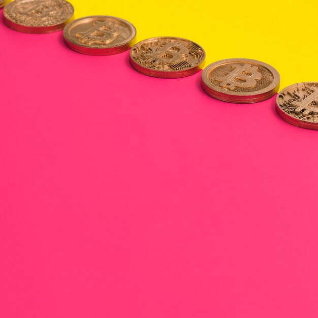 Rangée de plusieurs bitcoins sur le double fond jaune et rose